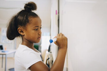 Schoolgirl writing on whiteboard at classroom - MASF12311