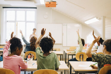 Students raising hands while answering in classroom at school - MASF12313