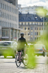 Full length of mature female commuter cycling on street in city - MASF12333