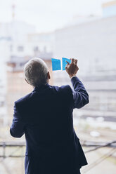 Rückansicht eines Geschäftsmannes, der Haftnotizen auf das Fensterglas klebt, während er im Kreativbüro eine Strategie plant - MASF12338