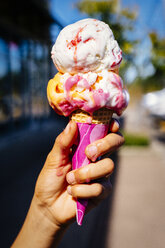 Hand of Mixed Race girl holding melting ice cream cone - BLEF01233