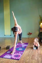 Gemischtrassige werdende Mutter, die Yoga praktiziert und ihre Tochter beobachtet - BLEF01283