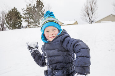 Smiling boy throwing snowball in winter - BLEF01298