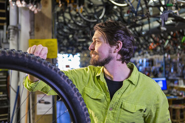 Kaukasischer Arbeiter, der in einer Werkstatt ein Fahrradrad repariert - BLEF01317