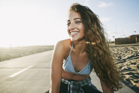 Porträt einer lächelnden kaukasischen Frau auf einem Weg am Strand, lizenzfreies Stockfoto