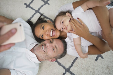 Familie liegt auf dem Boden und posiert für ein Selfie mit dem Handy - BLEF01328