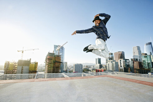 Schwarzer Mann tanzt und springt auf dem Dach einer Stadt - BLEF01336