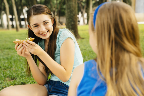 Smiling Caucasian sisters eating food at picnic - BLEF01404