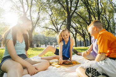 Lächelnde kaukasische Familie isst Essen beim Picknick - BLEF01405