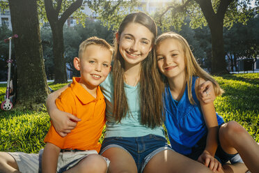Portrait of smiling Caucasian brother and sisters hugging in park - BLEF01414