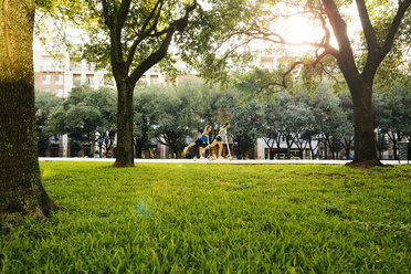 Distant Caucasian girls riding scooter in park - BLEF01435