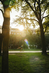 Distant Caucasian girl riding scooter in park - BLEF01437