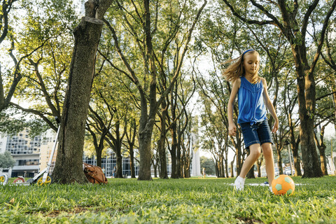 Kaukasisches Mädchen kickt Fußball im Park, lizenzfreies Stockfoto