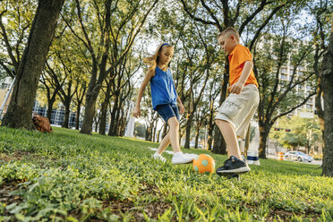 Kaukasischer Bruder und Schwester kicken Fußball im Park - BLEF01441