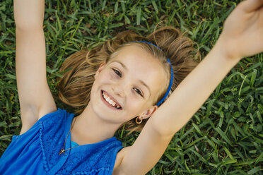 Close up portrait of smiling Caucasian girl laying on grass - BLEF01442