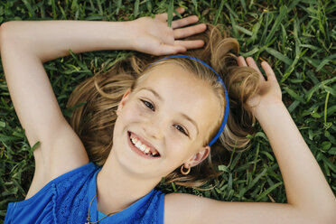 Close up portrait of smiling Caucasian girl laying on grass - BLEF01443