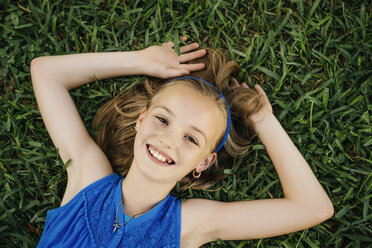 Close up portrait of smiling Caucasian girl laying on grass - BLEF01444