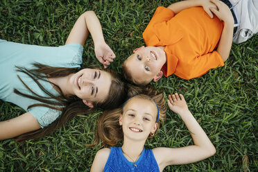 Close up portrait of smiling Caucasian brother and sisters laying on grass - BLEF01446