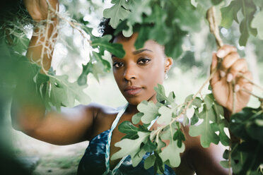 Portrait of serious mixed race woman holding tree branches - BLEF01467