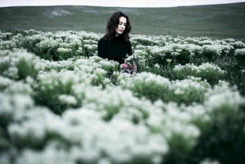 Kaukasische Frau in einem Feld mit Wildblumen stehend - BLEF01515