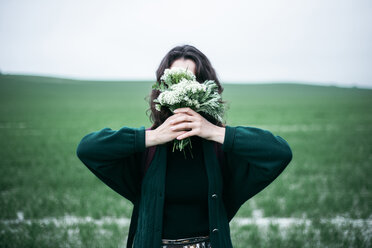 Kaukasische Frau hält Wildblumen vor das Gesicht - BLEF01516