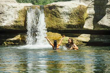 Kaukasisches Paar schwimmt in der Nähe eines Wasserfalls - BLEF01528