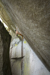 Mixed race boy hanging from rock - BLEF01583