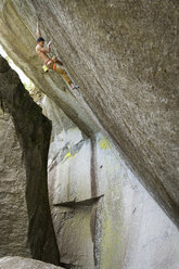 Gemischtrassiger Junge klettert auf Felsen - BLEF01584