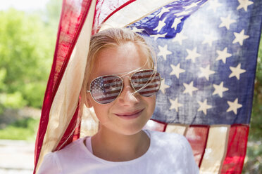 Kaukasisches Mädchen mit Sonnenbrille unter amerikanischer Flagge - BLEF01593