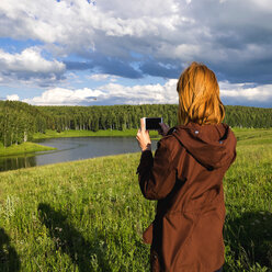 Frau fotografiert Fluss mit Mobiltelefon - BLEF01615