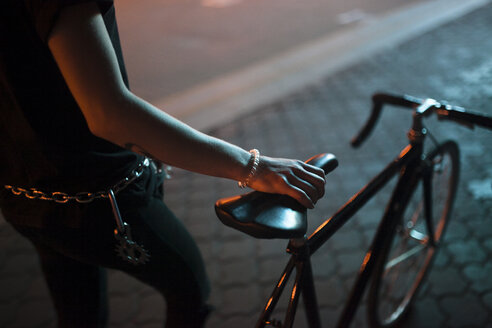 Caucasian man holding a bicycle seat at night - BLEF01627
