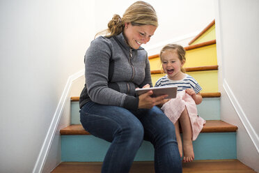 Kaukasische Mutter und Tochter benutzen ein digitales Tablet auf einer Treppe - BLEF01665