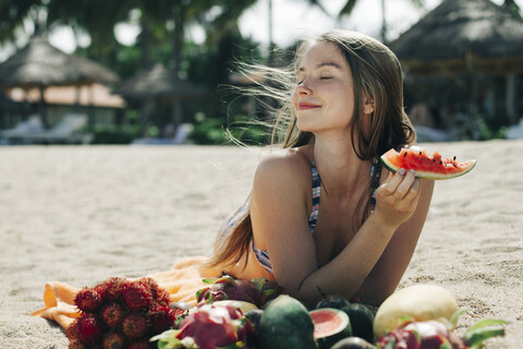 Kaukasische Frau isst Wassermelone am Strand, lizenzfreies Stockfoto