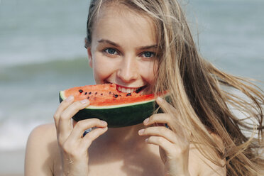 Caucasian woman eating watermelon on beach - BLEF01685