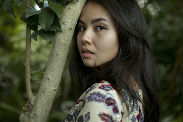 Portrait of Asian woman leaning forehead on tree branch - BLEF01695