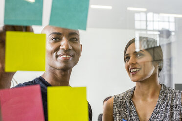 Woman and man reading adhesive notes in office - BLEF01702