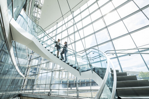 Entfernte gemischtrassige Geschäftsleute, die auf einer Treppe stehen und sich unterhalten, lizenzfreies Stockfoto