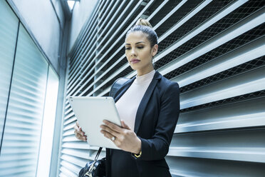 Serious Mixed Race businesswoman using digital tablet in corridor - BLEF01744