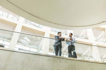 Gemischtrassige Geschäftsleute im Gespräch in der Lobby mit digitalem Tablet - BLEF01745