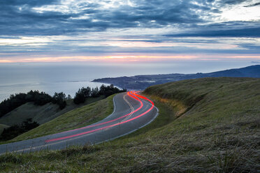 Light trails on winding road near ocean - BLEF01747