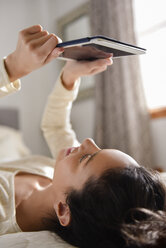 Hispanische Frau liegt auf dem Bett und liest auf einem digitalen Tablet - BLEF01773