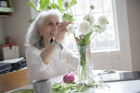 Ältere Frau arrangiert Blumen - BLEF01783