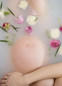 Caucasian expectant mother in milk bath with flowers - BLEF01795