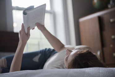 Caucasian woman laying on bed reading book - BLEF01797