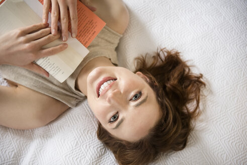 Kaukasische Frau liegt auf dem Bett und liest ein Buch - BLEF01798