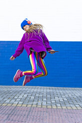 Happy girl with headphones and smartphone jumping in the air - ERRF01208