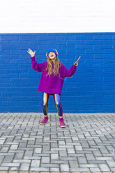 Singing girl listening music with headphones in front of blue wall - ERRF01217