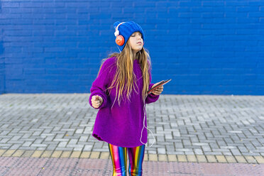 Girl dancing outdoors while listening music with headphones and smartphone - ERRF01219