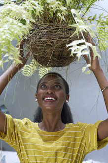 Glückliche junge Frau, die eine Pflanze hält - VEGF00098