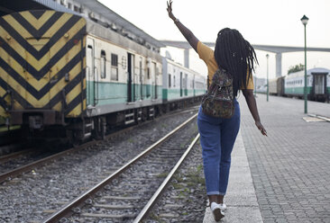 Rear view of young woman at the edge of the rail at the train station - VEGF00116